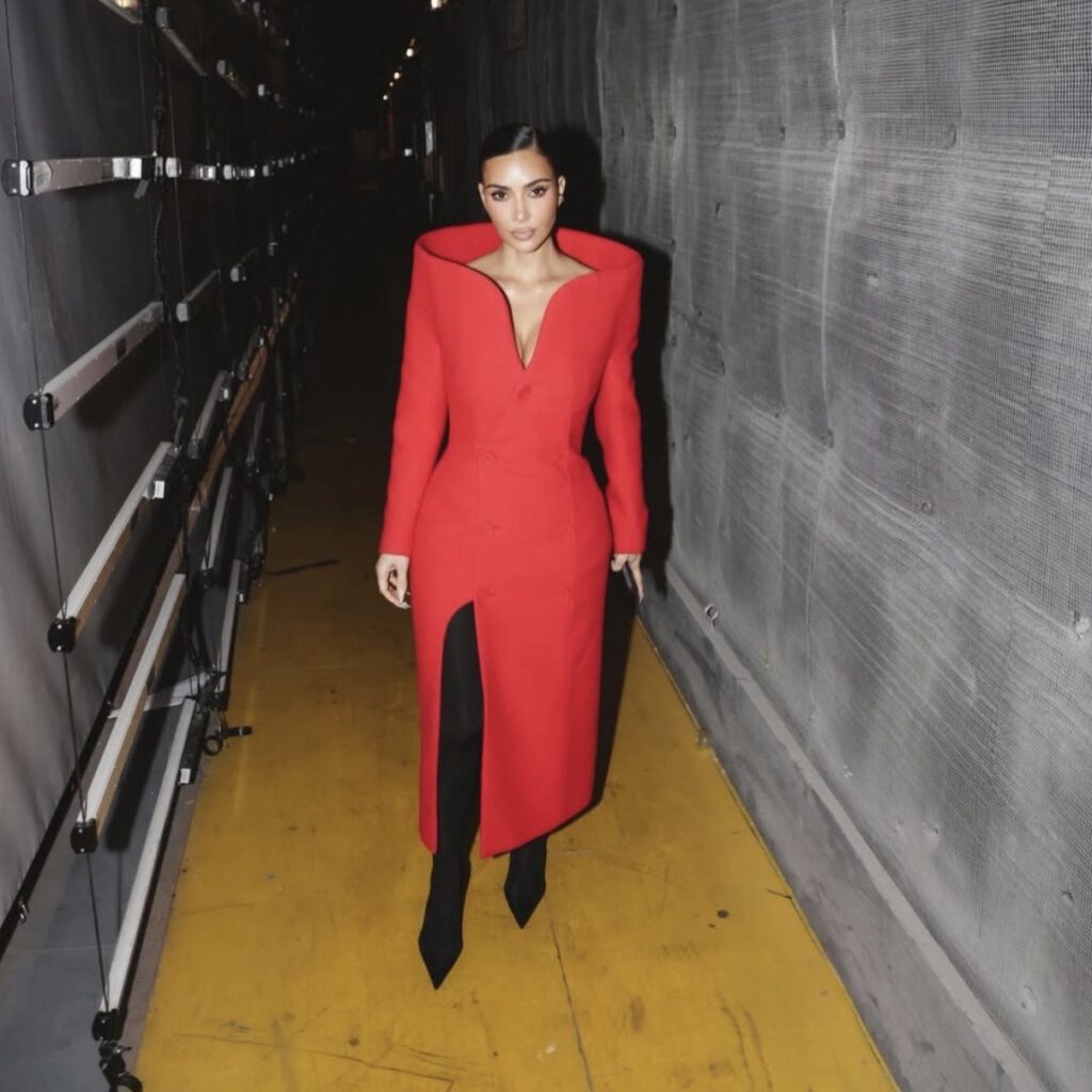 Kim Kardashian in a bold red Balenciaga tailored coat styled with black boots, a striking take on modern celebrity new year outfits.