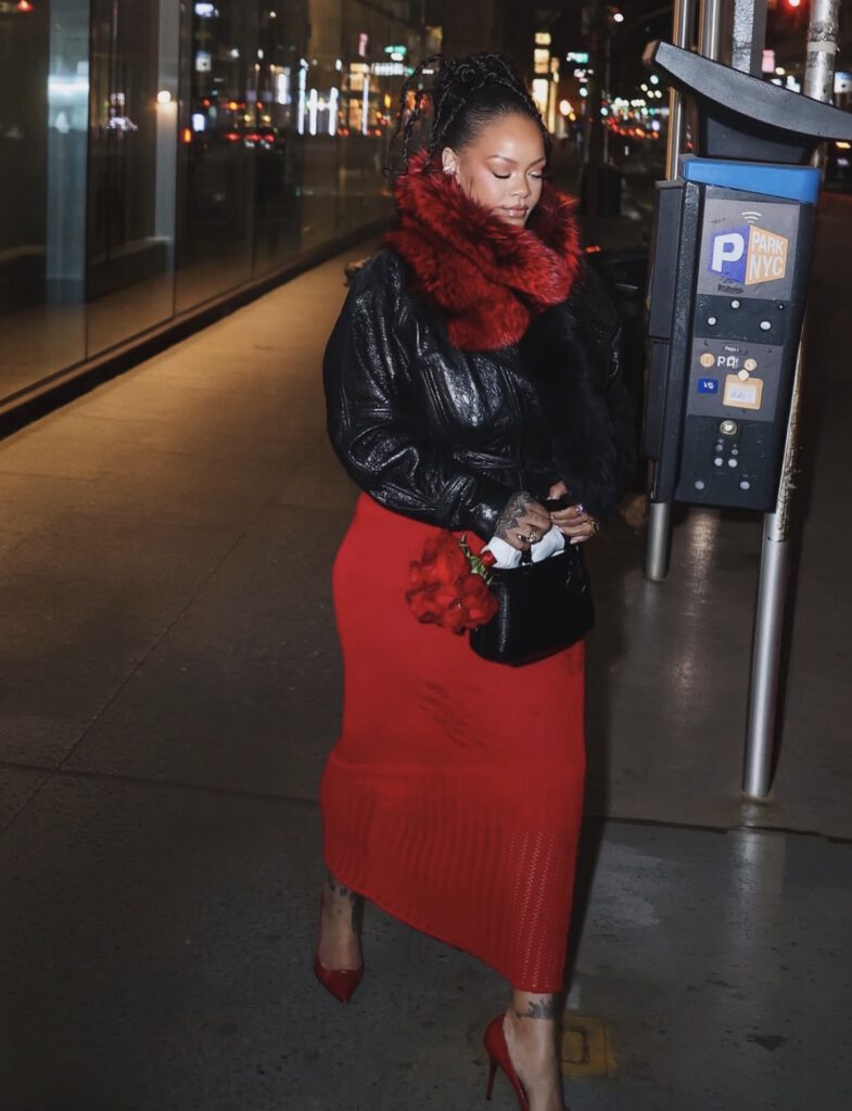 Rihanna in a sheer ruby red knit column dress layered with a black leather jacket and red pumps for a bold Valentine’s Day celebrity look — Edgy celebrity outfits.