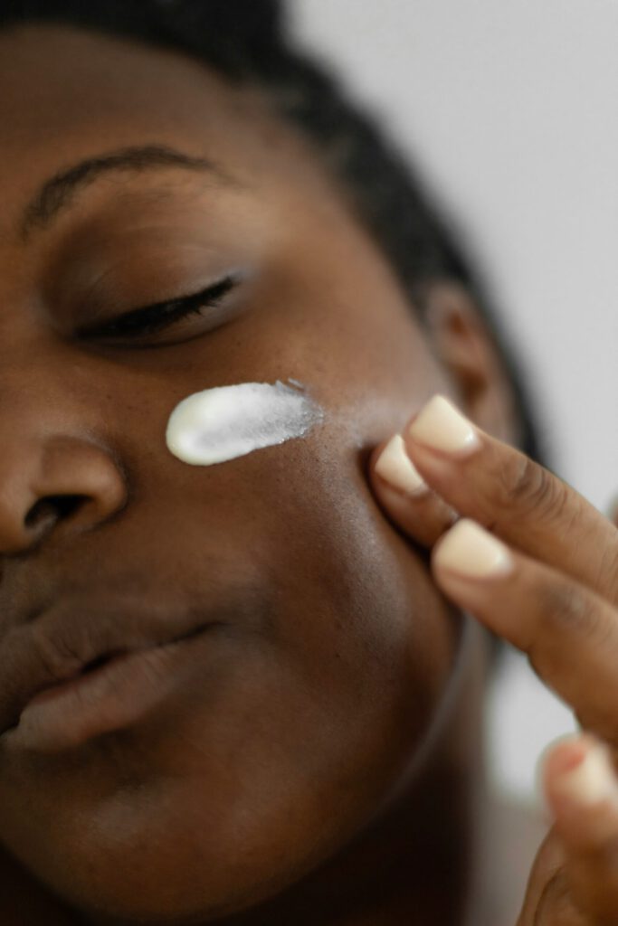 black woman applies african botanicals skincare on face