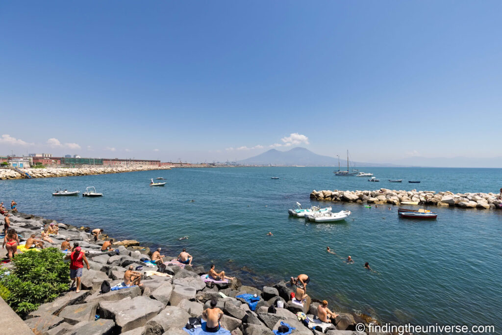 View of Vesuvius from Naples waterfront with people bathing by Laurence Norah-2